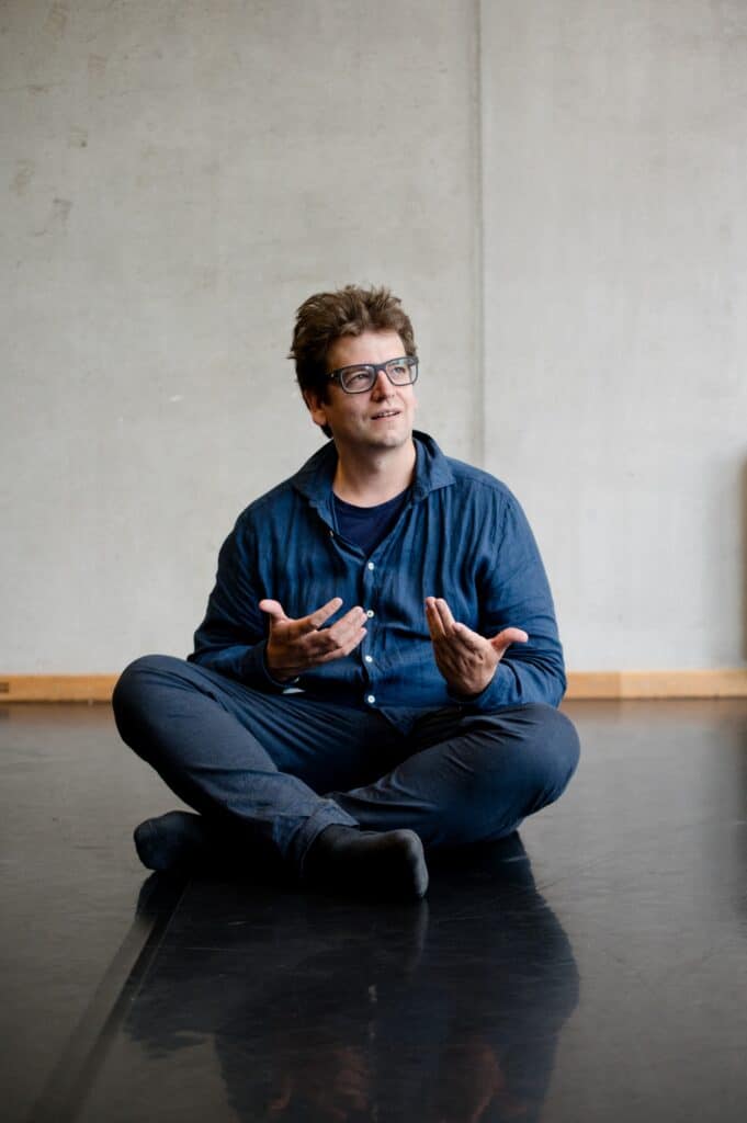 Christoph Galette im Schneidersitz auf dem Boden